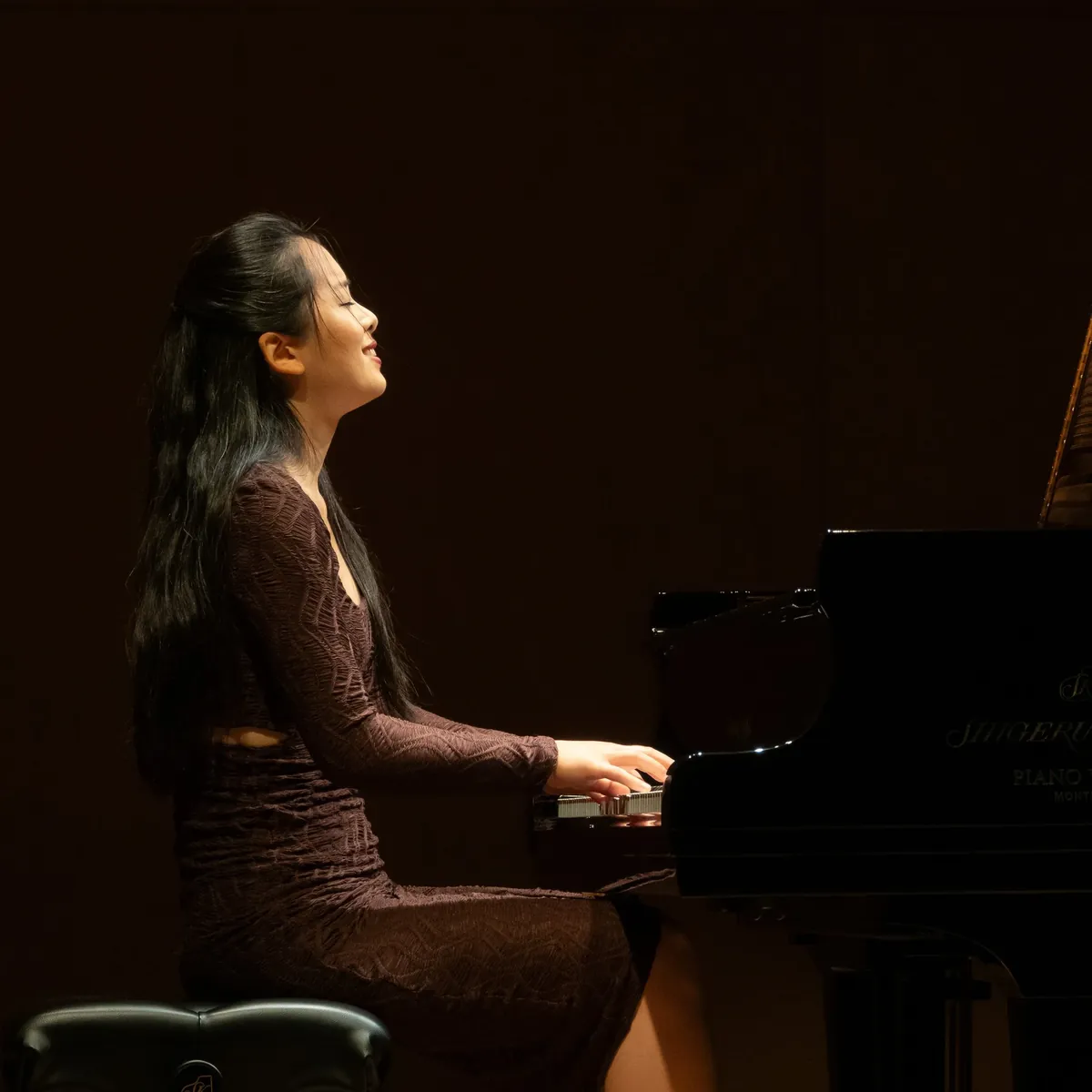Fiona Wu au piano, en concert, le visage tourné vers la lumière