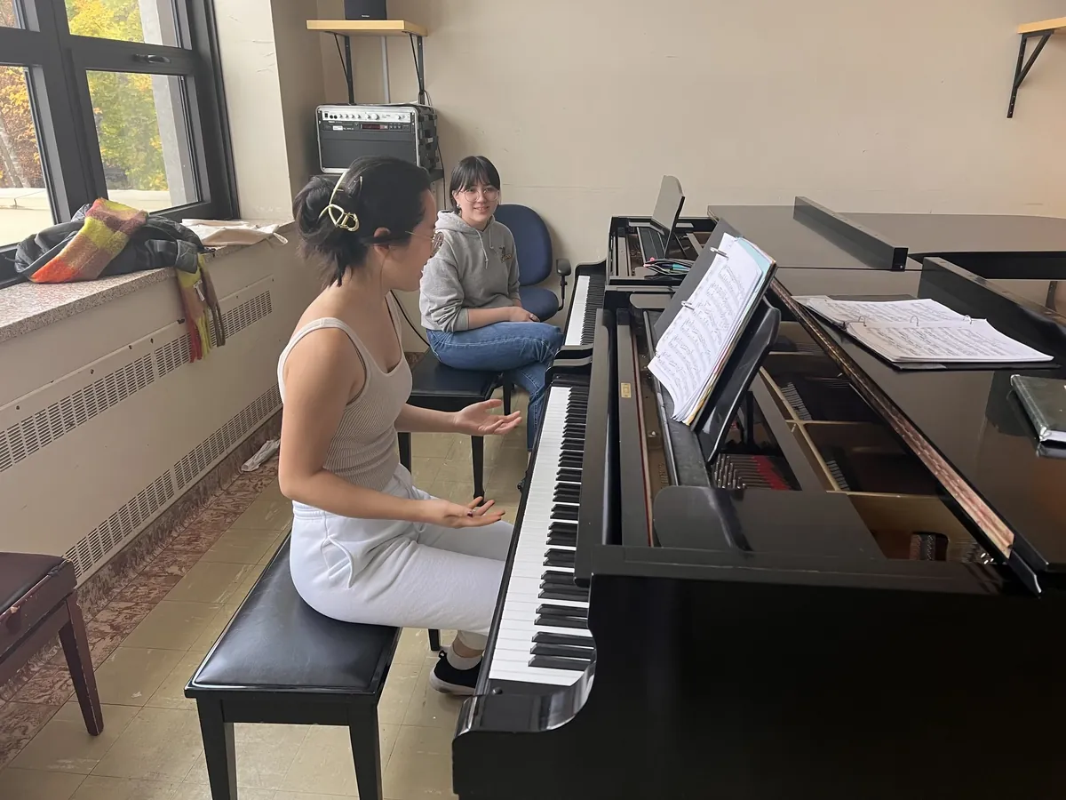 Fiona Wu au piano pendant une leçon, une élève à ses côtés