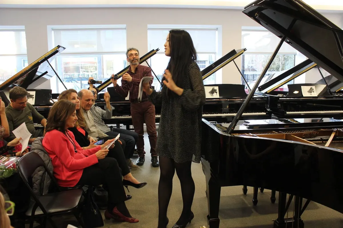 Fiona Wu s’adressant à un auditoire, entourée de pianos à queue
